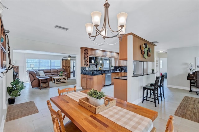 tiled dining space with ceiling fan with notable chandelier