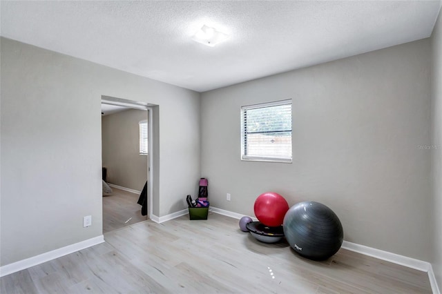 workout room with a textured ceiling, a healthy amount of sunlight, and light wood-type flooring