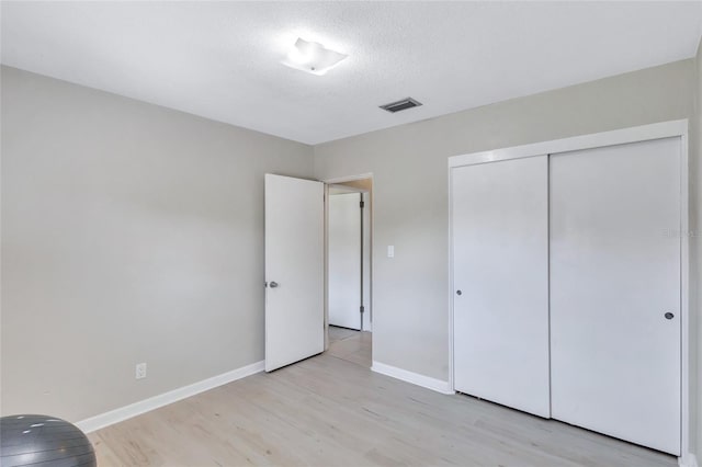 unfurnished bedroom featuring light hardwood / wood-style floors, a closet, and a textured ceiling