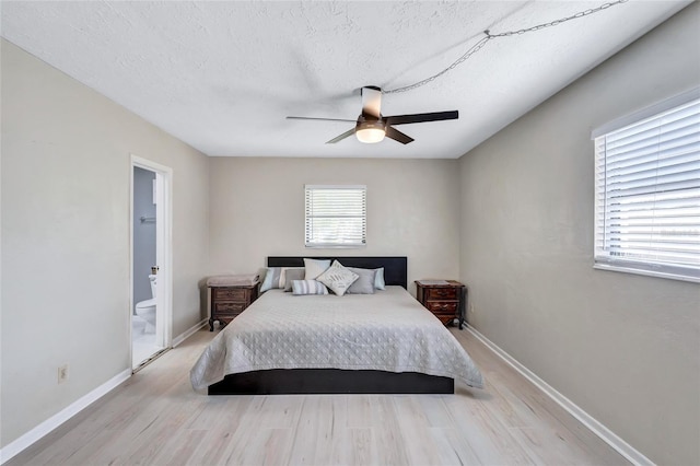 bedroom with ceiling fan, ensuite bathroom, a textured ceiling, and light wood-type flooring