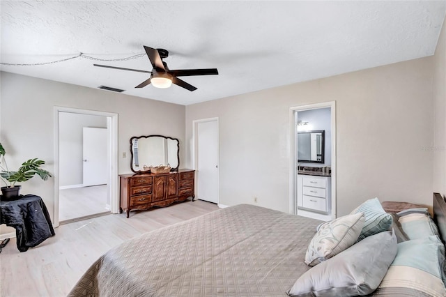 bedroom featuring ceiling fan, ensuite bath, and light wood-type flooring