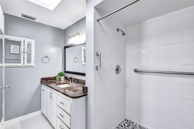 bathroom with vanity, tiled shower, and tile patterned floors