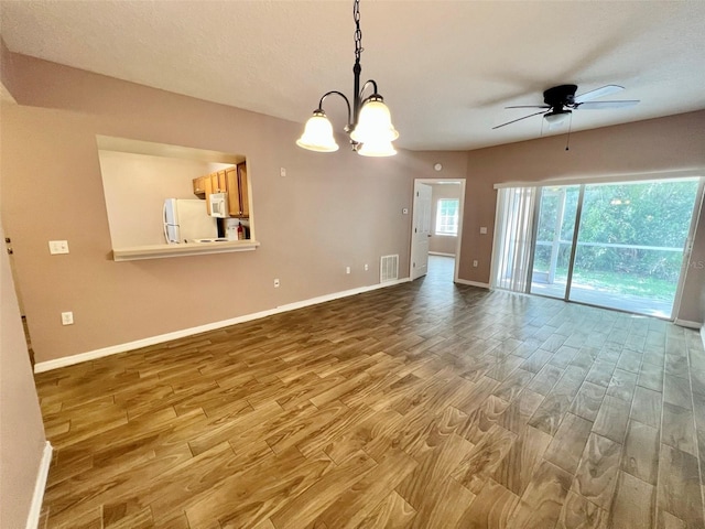 interior space with hardwood / wood-style floors and ceiling fan with notable chandelier