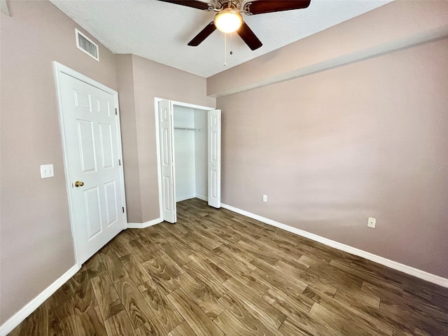 unfurnished bedroom with hardwood / wood-style flooring, a textured ceiling, ceiling fan, and a closet