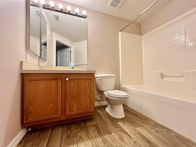 full bathroom featuring vanity, hardwood / wood-style floors, toilet, and a textured ceiling