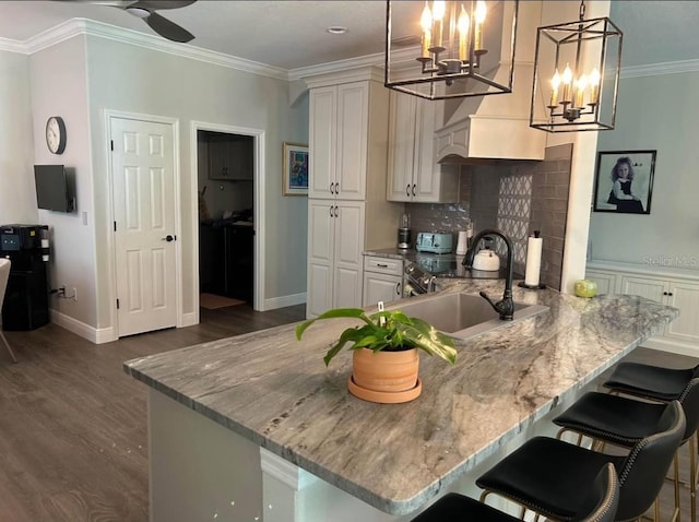 kitchen featuring hanging light fixtures, ornamental molding, a kitchen breakfast bar, and kitchen peninsula