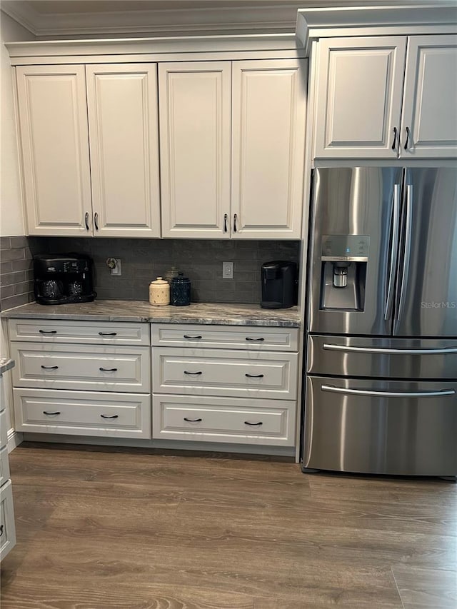 kitchen with dark wood-type flooring, stainless steel fridge, tasteful backsplash, ornamental molding, and white cabinets