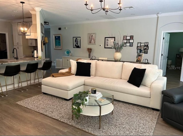 living room with crown molding, sink, hardwood / wood-style floors, and a notable chandelier