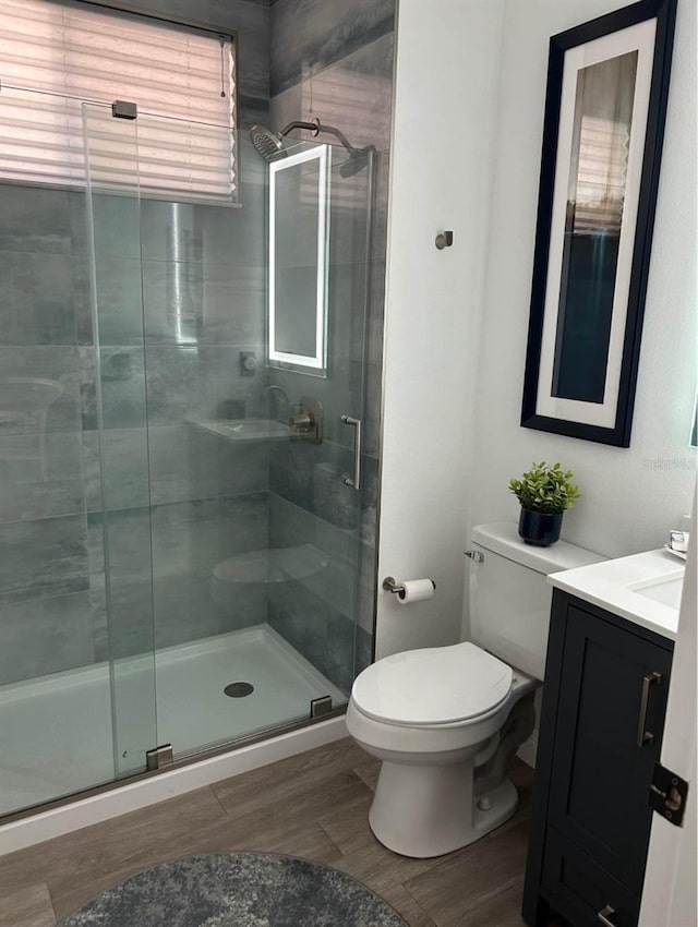 bathroom with walk in shower, hardwood / wood-style floors, vanity, and toilet