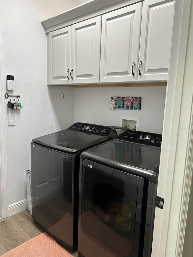 washroom with cabinets, separate washer and dryer, and light wood-type flooring