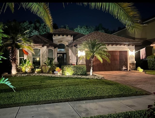 mediterranean / spanish house featuring a garage and a lawn