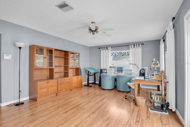 office space featuring a textured ceiling, light hardwood / wood-style flooring, a barn door, and ceiling fan