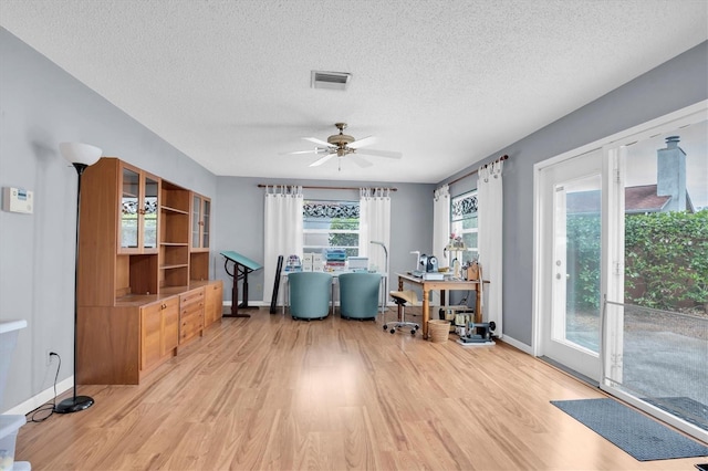 home office featuring ceiling fan, light hardwood / wood-style flooring, and a textured ceiling