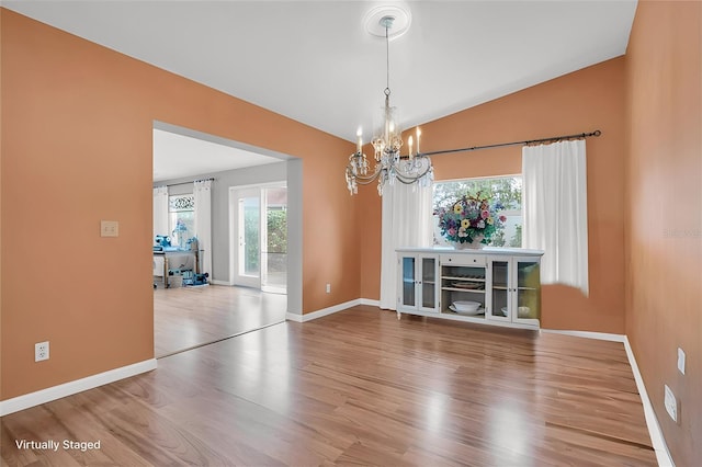 unfurnished dining area with vaulted ceiling, wood-type flooring, and a notable chandelier