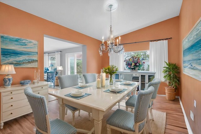 dining area with lofted ceiling, a chandelier, and light wood-type flooring