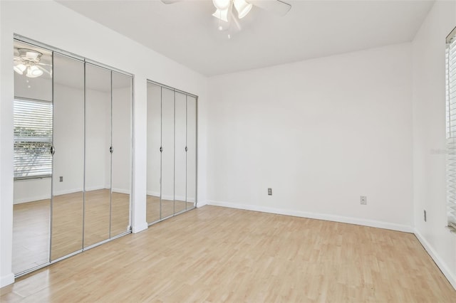 unfurnished bedroom featuring multiple closets, ceiling fan, and light hardwood / wood-style flooring