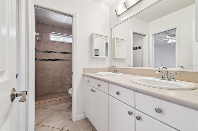 bathroom featuring tile patterned flooring, vanity, tiled shower, ceiling fan, and toilet