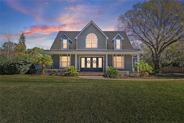 cape cod house featuring covered porch and a lawn