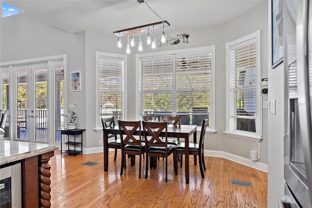 dining space featuring light hardwood / wood-style flooring, beverage cooler, and french doors