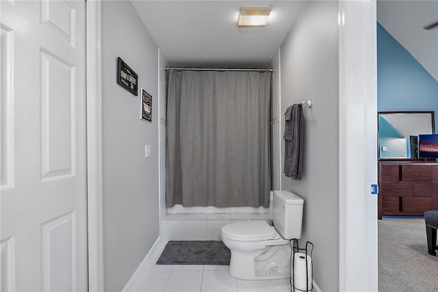 bathroom featuring a shower with curtain, toilet, tile patterned flooring, and a textured ceiling