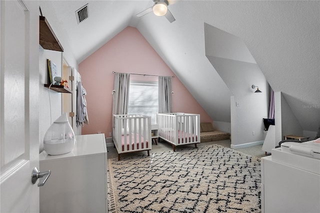 carpeted bedroom featuring a nursery area, lofted ceiling, and ceiling fan