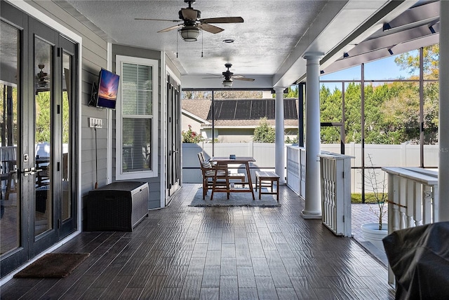 unfurnished sunroom with ceiling fan and decorative columns