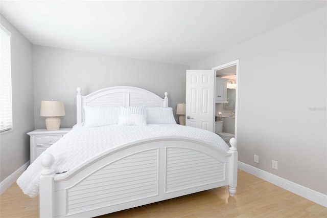 bedroom with ensuite bathroom and light hardwood / wood-style floors