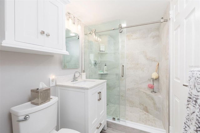 bathroom with vanity, a shower with door, and toilet