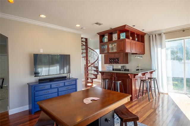 dining room with crown molding, indoor wet bar, and light hardwood / wood-style floors