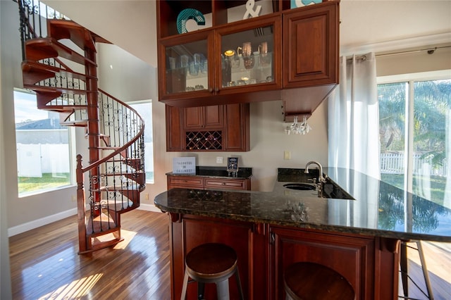 kitchen featuring sink, hardwood / wood-style flooring, a breakfast bar area, dark stone countertops, and kitchen peninsula