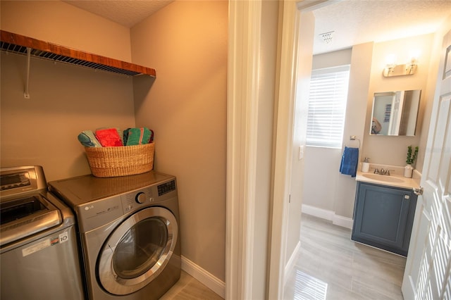 laundry room featuring sink, a textured ceiling, and washer and clothes dryer