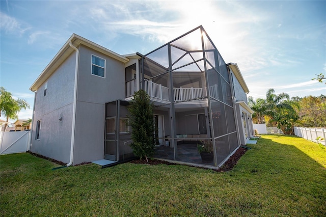 back of property with a balcony, a lanai, and a yard