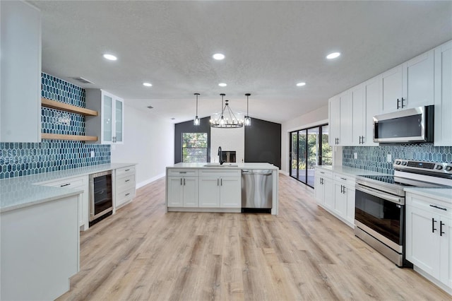 kitchen featuring pendant lighting, sink, appliances with stainless steel finishes, white cabinetry, and wine cooler