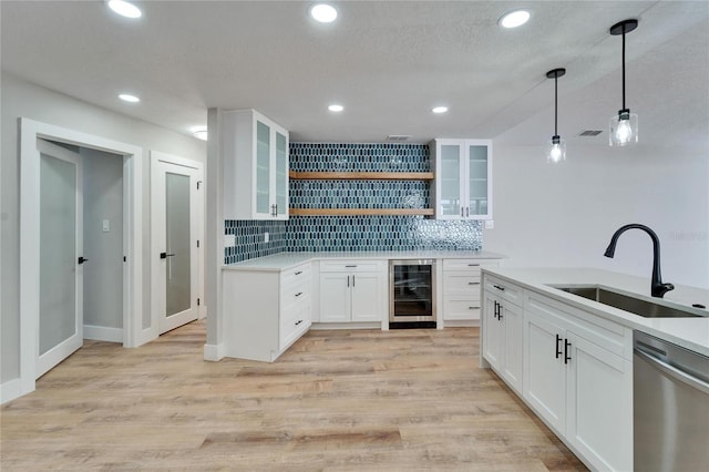 kitchen with sink, decorative light fixtures, dishwasher, beverage cooler, and white cabinets