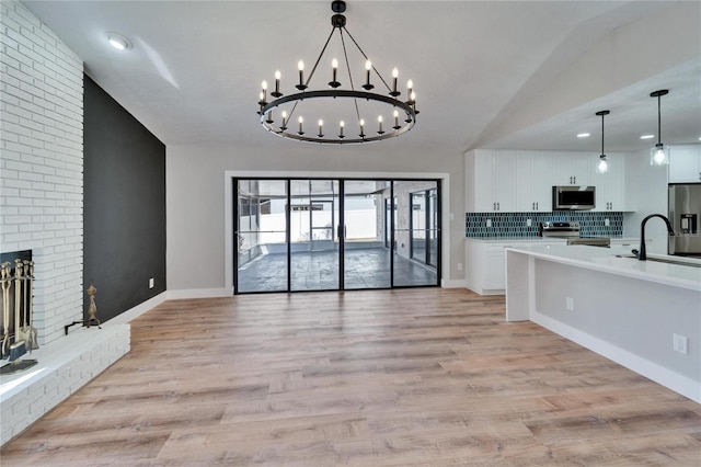 living room with sink, a fireplace, vaulted ceiling, and light wood-type flooring