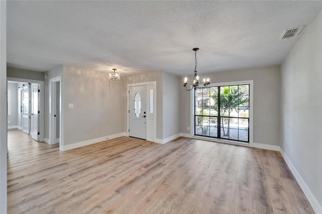 interior space with an inviting chandelier, a textured ceiling, light hardwood / wood-style flooring, and a healthy amount of sunlight