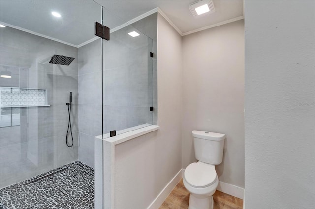 bathroom with tiled shower, ornamental molding, toilet, and hardwood / wood-style floors