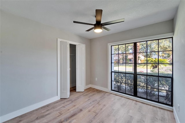 unfurnished bedroom with light hardwood / wood-style floors, a closet, and ceiling fan