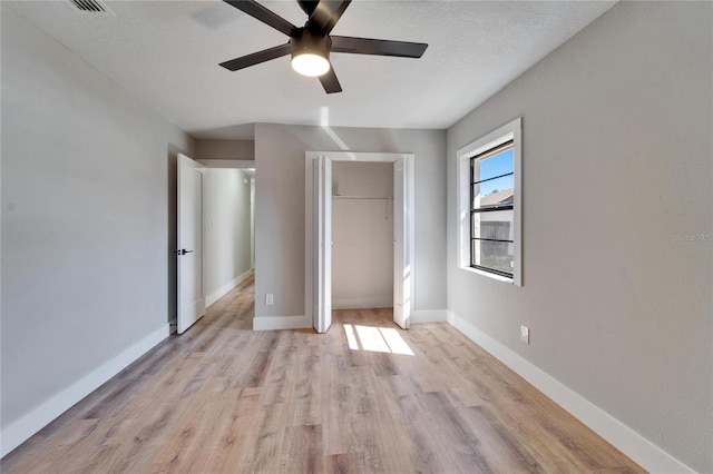 unfurnished bedroom with ceiling fan, light hardwood / wood-style floors, a closet, and a textured ceiling