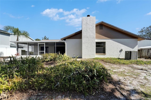 rear view of property with central AC unit and a sunroom