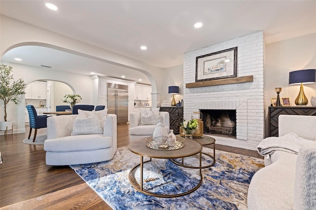 living room featuring a brick fireplace and dark hardwood / wood-style flooring