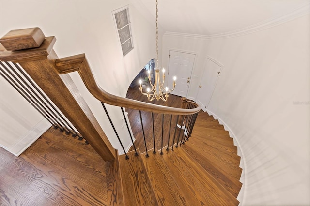 stairs featuring a notable chandelier, wood-type flooring, and ornamental molding