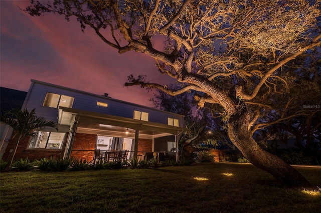 back house at dusk featuring a yard