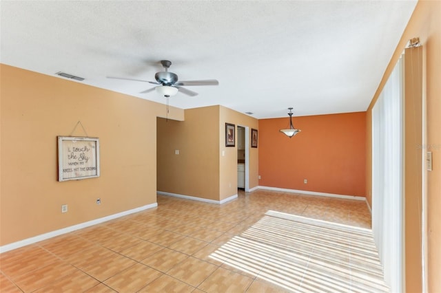 empty room with tile patterned flooring, ceiling fan, and a textured ceiling