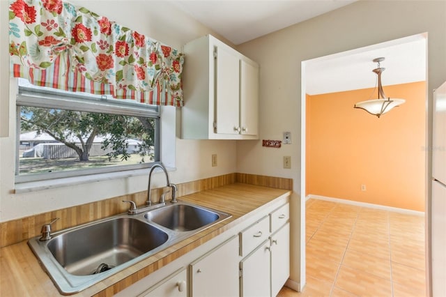 kitchen with white cabinetry, decorative light fixtures, sink, and light tile patterned floors