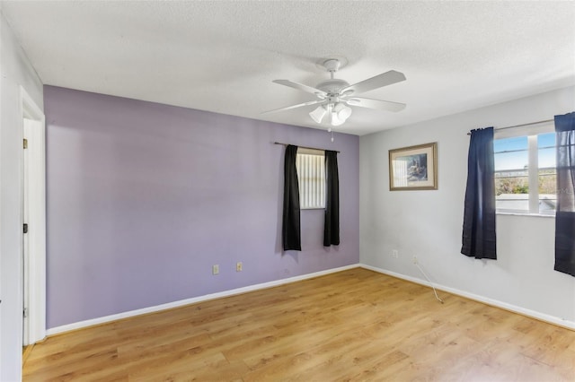 empty room featuring ceiling fan, light hardwood / wood-style flooring, and a textured ceiling