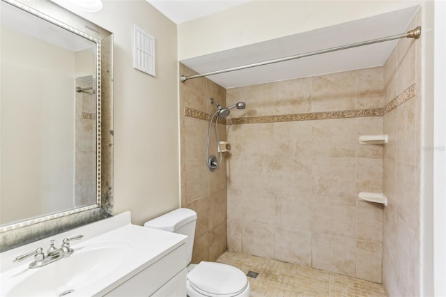 bathroom with tiled shower, vanity, and toilet