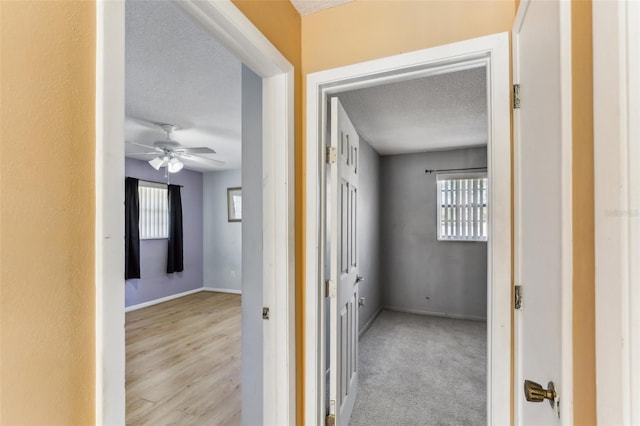 hallway featuring light colored carpet and a textured ceiling