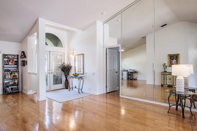 foyer entrance featuring hardwood / wood-style floors, high vaulted ceiling, and french doors