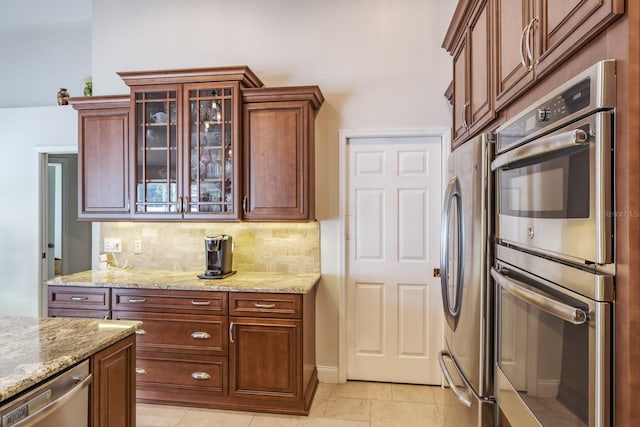 kitchen featuring light stone counters, light tile patterned floors, backsplash, and appliances with stainless steel finishes